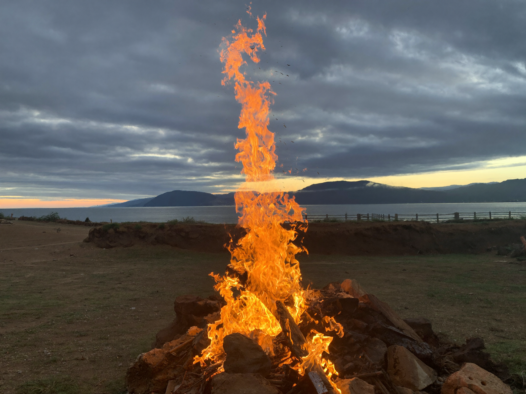 A large wood burning fire pit with tall flames, the kind of substantial fire bed that needs the full drown, stir, drown sequence rather than a single pass of water.