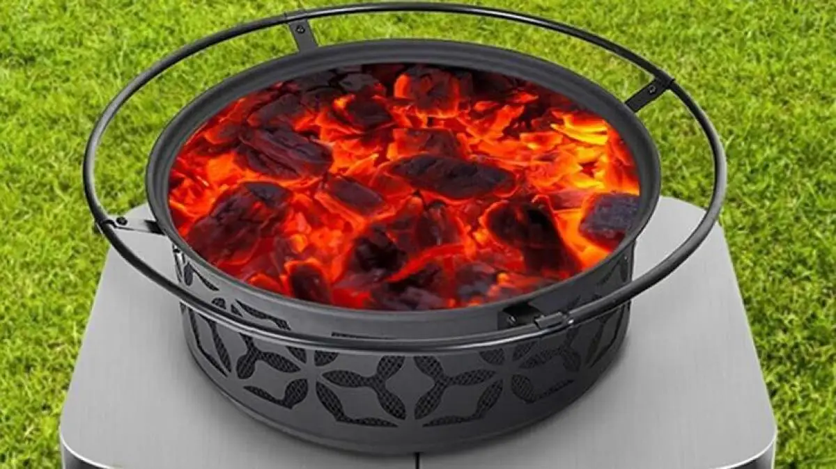 A circular heat-resistant deck shield pad resting on a cedar wood deck, underneath the metal legs of a portable fire pit.
