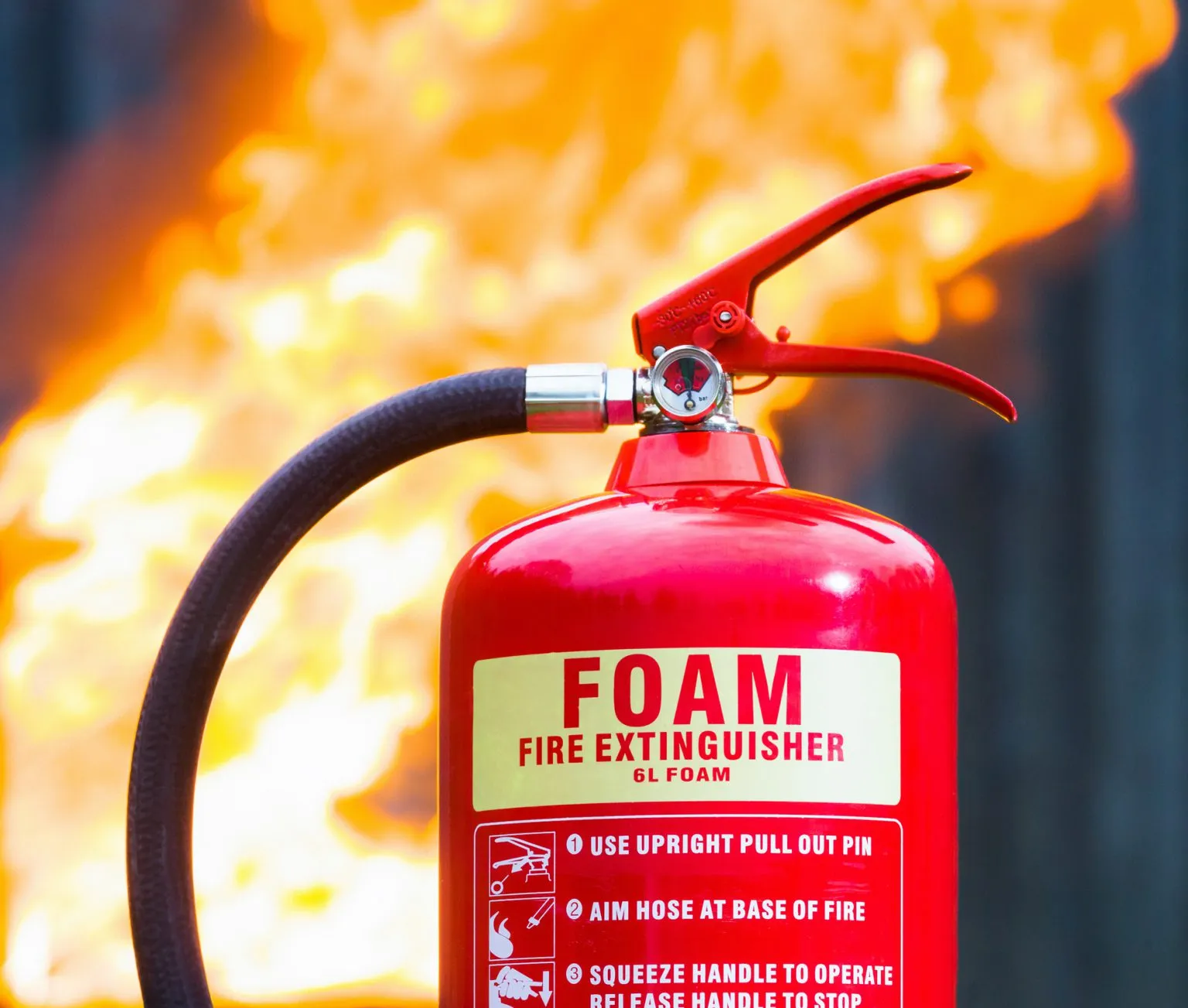 An outdoor safety kit with a fire extinguisher, heat-resistant leather gloves, and a safety checklist laid out neatly on concrete.