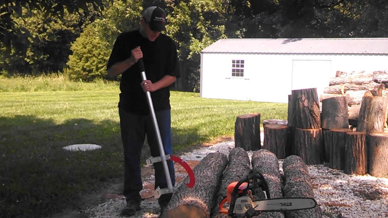 A set of long, wrought-iron firewood tongs grabbing a dry split log, demonstrating safe distance log management.