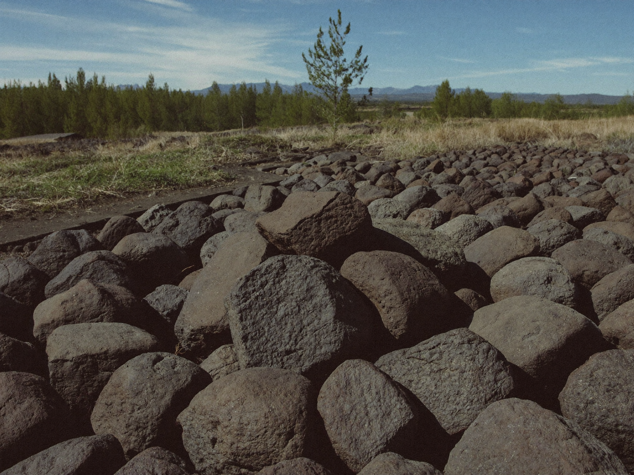 Lava rocks filling the burner pan of a gas fire pit with flames rising evenly through the porous volcanic rock
