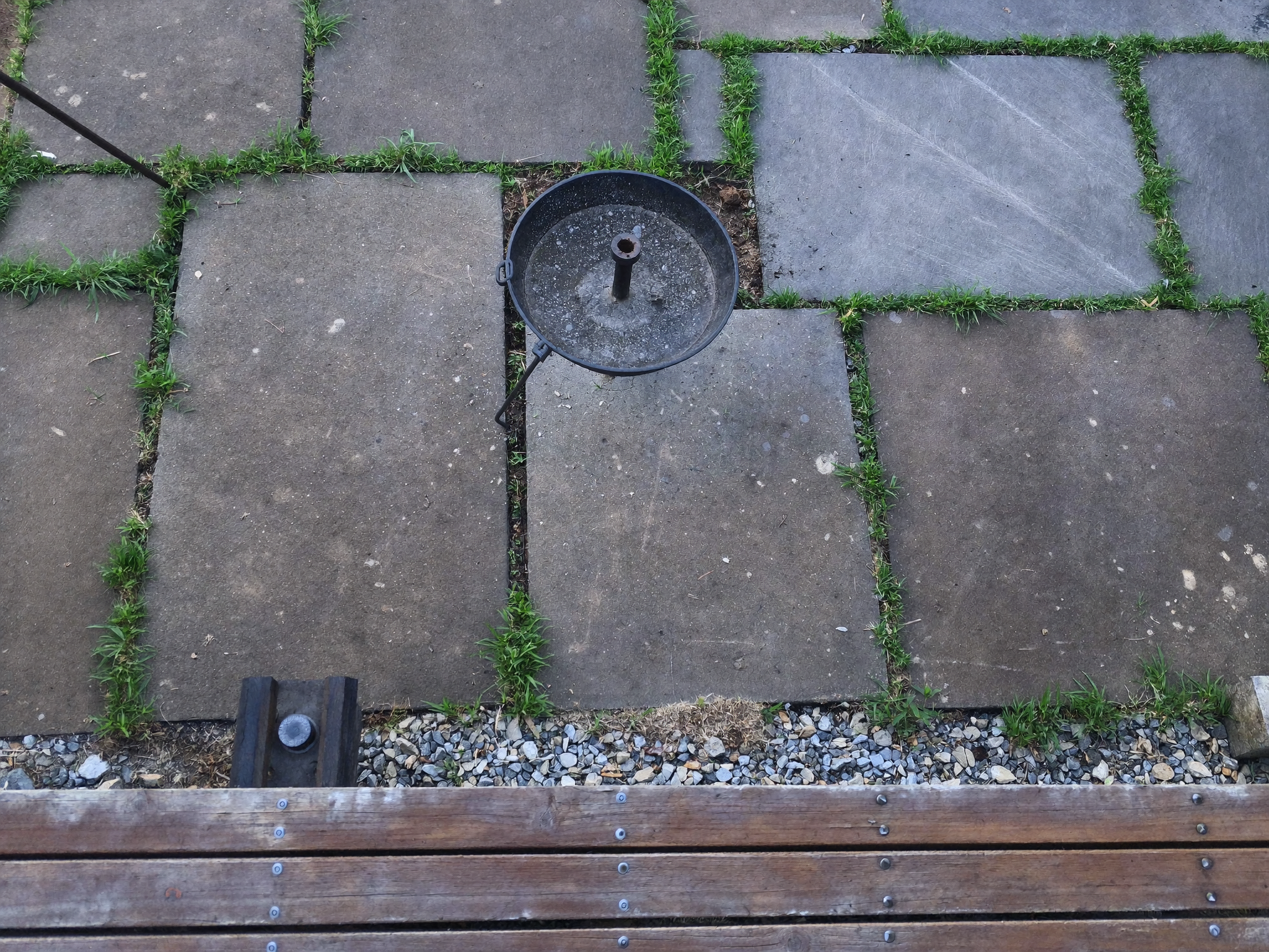 Fire pit positioned over a protected outdoor surface with pavers, grass, concrete, and decking visible underneath